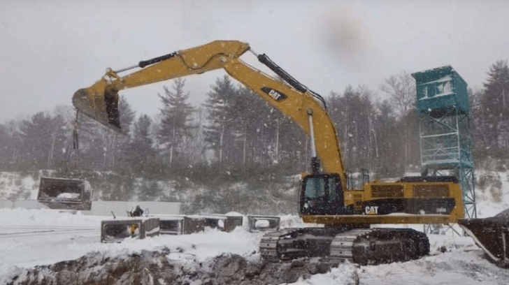 A piece of yellow machinery on a snowy construction site in the winter